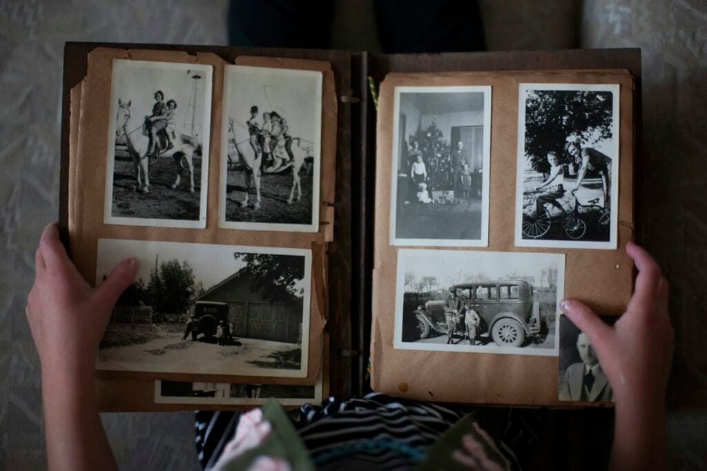 Genealogy Research for Your Lorraine Ancestor 4 Mains feuilletant un album de photos de famille anciennes en noir et blanc