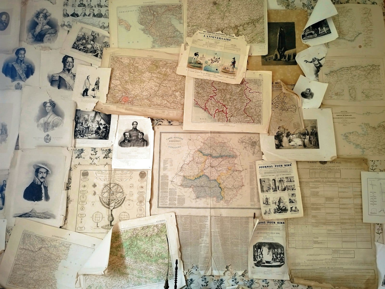 Cartes anciennes et photos d’archives étalées sur une table de recherche généalogique