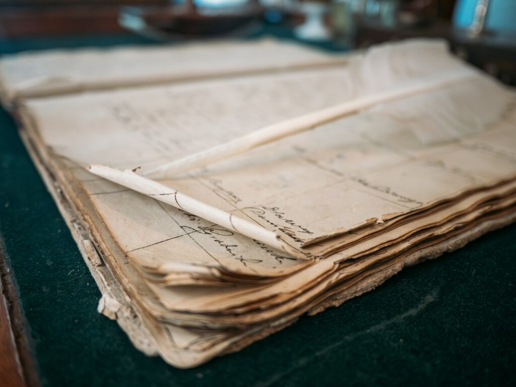 Vieux registre manuscrit ouvert, une plume posée sur les pages