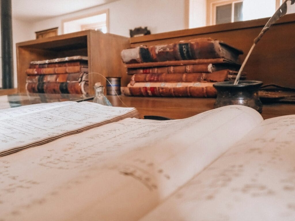 Registres paroissiaux de la Moselle : retrouver vos ancêtres avant 1793 1 Registre ancien ouvert sur un bureau, avec de vieux livres et une plume